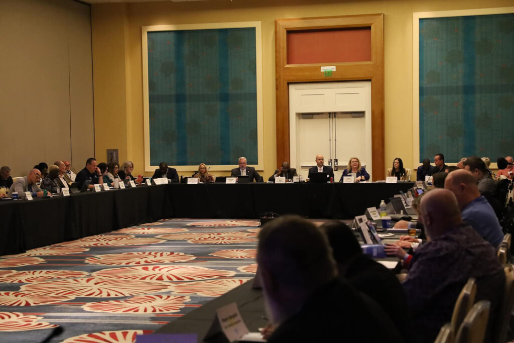 Committee members at a table addressing a crowd