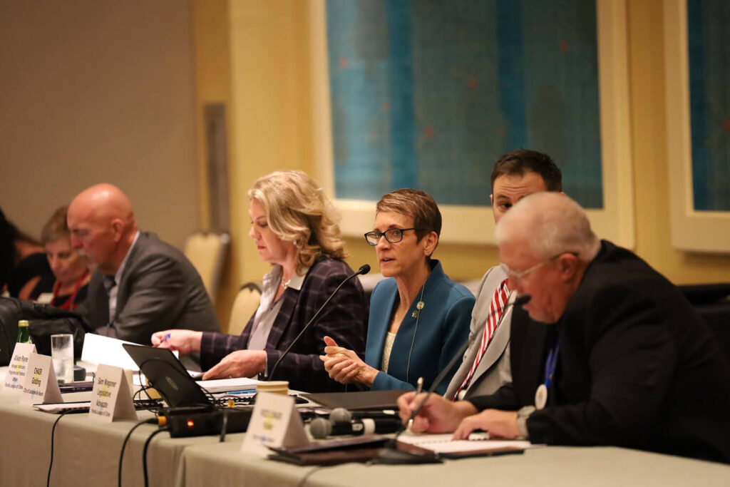 Committee members at a table addressing a crowd